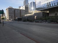 an empty street in a big city near tall buildings, and cars driving on the road