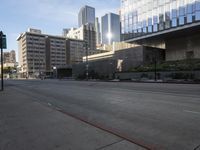 an empty street in a big city near tall buildings, and cars driving on the road