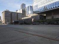 an empty street in a big city near tall buildings, and cars driving on the road