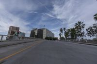 a car is driving on a road with tall buildings in the background and palm trees