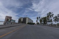 a car is driving on a road with tall buildings in the background and palm trees