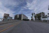 a car is driving on a road with tall buildings in the background and palm trees