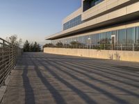 there is a metal rail next to a walkway with railings and a large building in the background