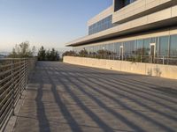 there is a metal rail next to a walkway with railings and a large building in the background