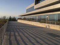 there is a metal rail next to a walkway with railings and a large building in the background