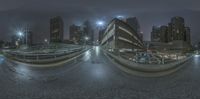 a city at night showing the light on a street bridge and a parking lot with cars parked