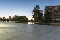 a skateboarder riding uphill on a sidewalk in an urban setting at dusk