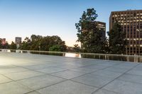 a skateboarder riding uphill on a sidewalk in an urban setting at dusk