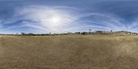 a 360 - up panoramic view of an open field showing an intersection with a sky background