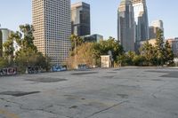 an empty parking lot with graffiti covered walls in front of tall buildings and trees in the distance