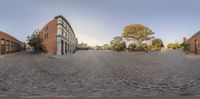 a view of an empty street with red brick buildings and buildings around it, taken through a fish - eye lens