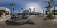 this is a very wide panoramic view of a street with buildings and palm trees in the background