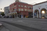 a street intersection with people and a building on both sides of the street at sunset