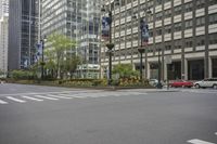 the empty street is lined with parked cars and tall buildings with flowers on each side