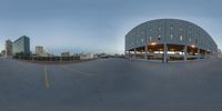 a fisheye photo shows a parking lot and buildings with a building in the background