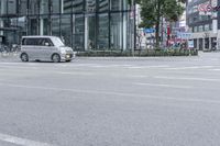 an empty city street with a large building and bicycles parked beside it in the background