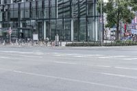 an empty city street with a large building and bicycles parked beside it in the background