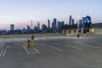 an empty parking lot with a clock tower in the background in the foreground with a view of city and skyscrapers