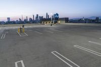 an empty parking lot with a clock tower in the background in the foreground with a view of city and skyscrapers