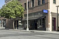 people walking on a street past tall buildings near a cross walk with tables and chairs in front of it