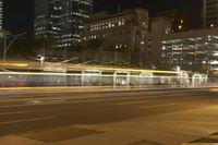 the light rail is shining on a street corner with buildings in the background at night