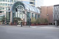a man walks down the sidewalk in front of a glassy building with a clock on it
