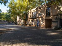 an empty street with buildings and trees on both sides of the road, with sidewalk pavers