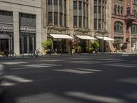 a picture of a street with several people walking and bicycles parked and two people walking with their hands in the ground