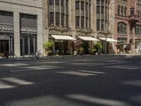 a picture of a street with several people walking and bicycles parked and two people walking with their hands in the ground