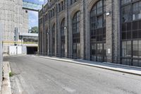 a building with tall windows and a brick sidewalk with no cars on it in front