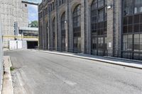 a building with tall windows and a brick sidewalk with no cars on it in front