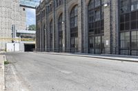 a building with tall windows and a brick sidewalk with no cars on it in front