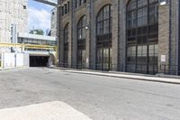 a building with tall windows and a brick sidewalk with no cars on it in front