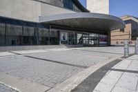 a person sitting at the bench in front of a mall that is empty of people