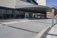 a person sitting at the bench in front of a mall that is empty of people