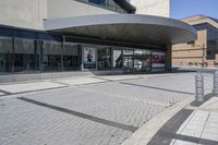 a person sitting at the bench in front of a mall that is empty of people