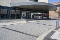 a person sitting at the bench in front of a mall that is empty of people