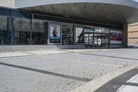 a person sitting at the bench in front of a mall that is empty of people