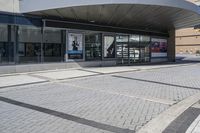 a person sitting at the bench in front of a mall that is empty of people