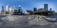 a wide angle view of a curved building in front of other tall buildings, from the ground up