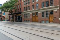 a street with a sidewalk, a train track and many windows in the building side