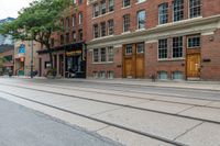 a street with a sidewalk, a train track and many windows in the building side