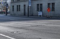 a street corner that is empty with an orange arrow on the curb and cars driving on it