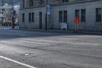 a street corner that is empty with an orange arrow on the curb and cars driving on it