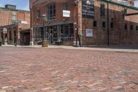 an empty brick city street in a downtown area, with many stores and buildings on each side