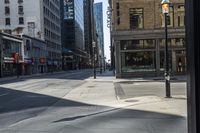 the view from the inside of a bus window of the street between the buildings on which a street sign indicates the intersection and there is empty