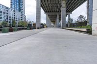 empty roadway with concrete buildings and overpass above it in city area with blue sky