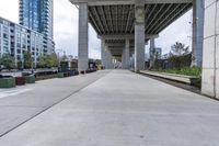 empty roadway with concrete buildings and overpass above it in city area with blue sky