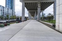 empty roadway with concrete buildings and overpass above it in city area with blue sky