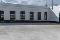 an empty parking lot with a train parked nearby and people walking by the door to the station